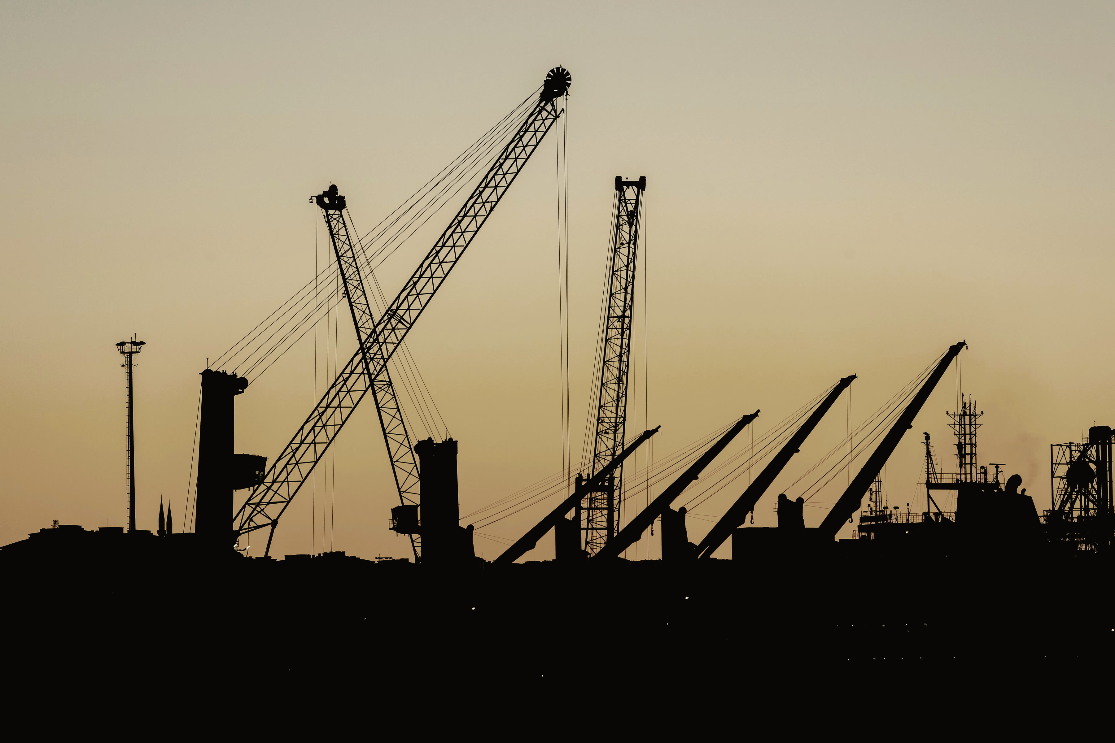 A large construction site at dusk, cranes standing over an unfinished frame.