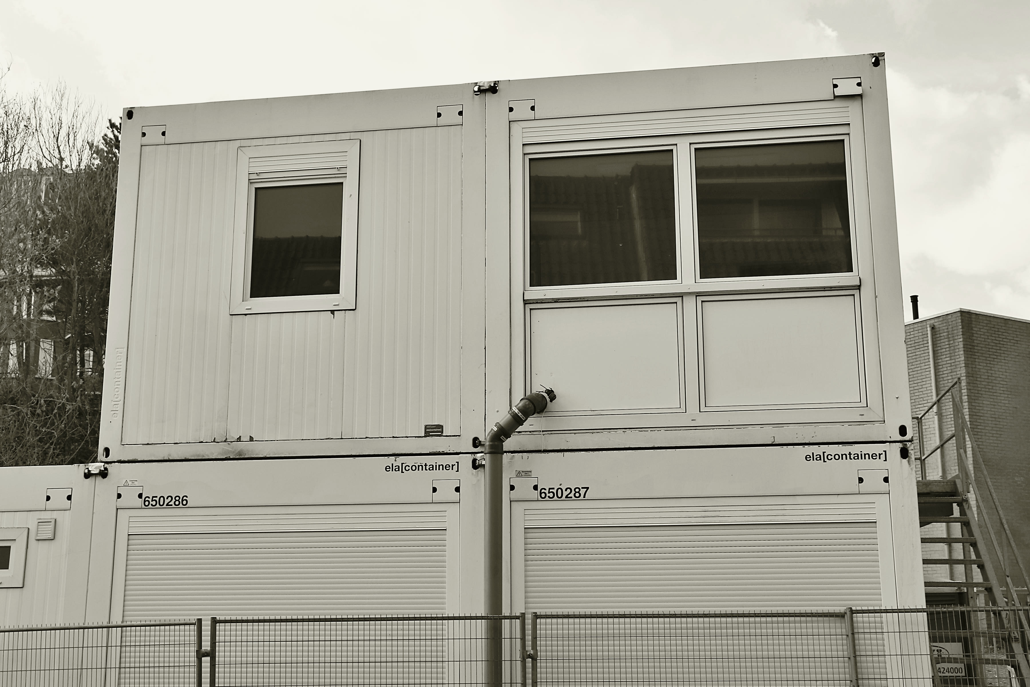 A site compound of stacked temporary offices and welfare cabins.