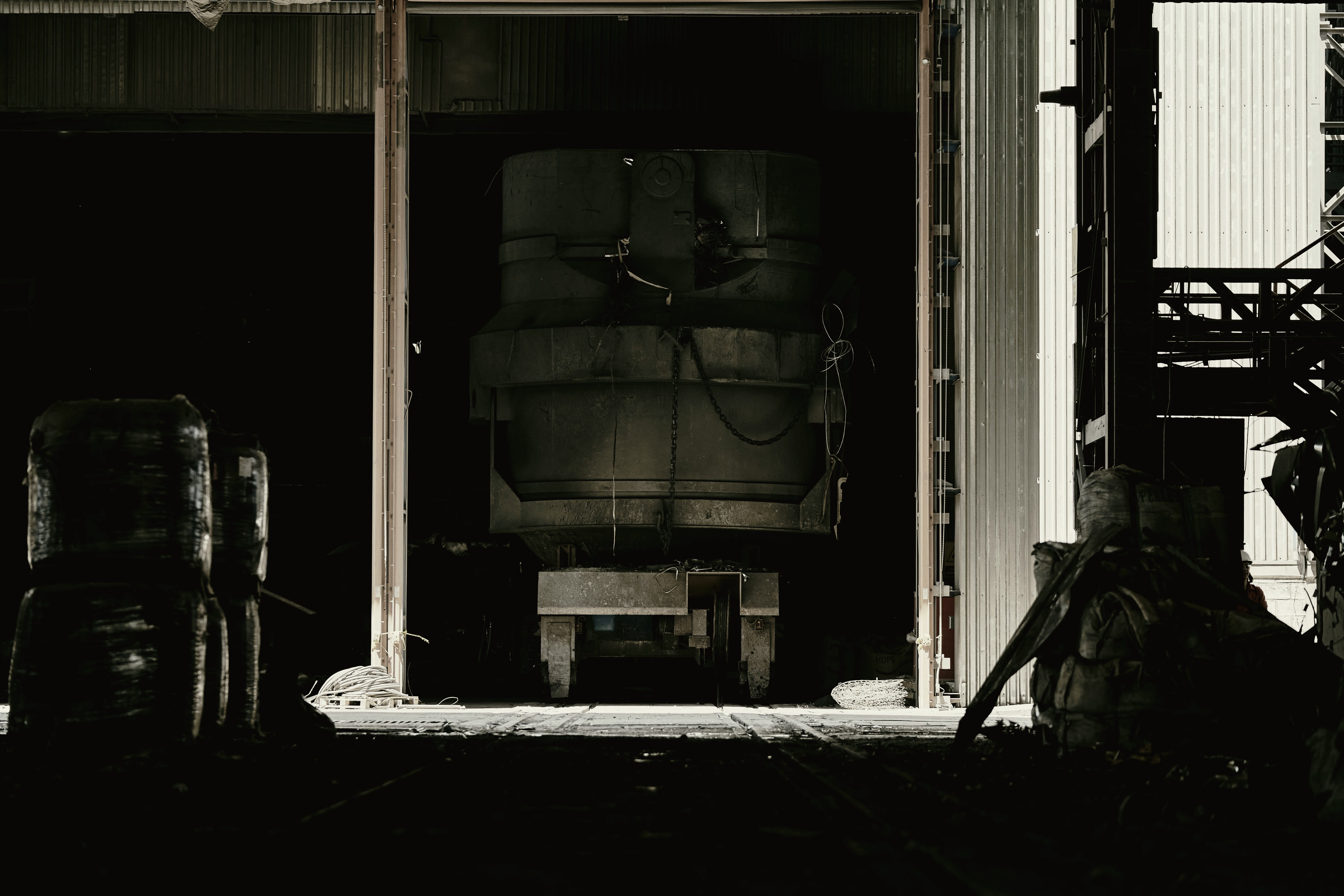 Heavy plant standing in the mouth of an industrial bay at dusk.
