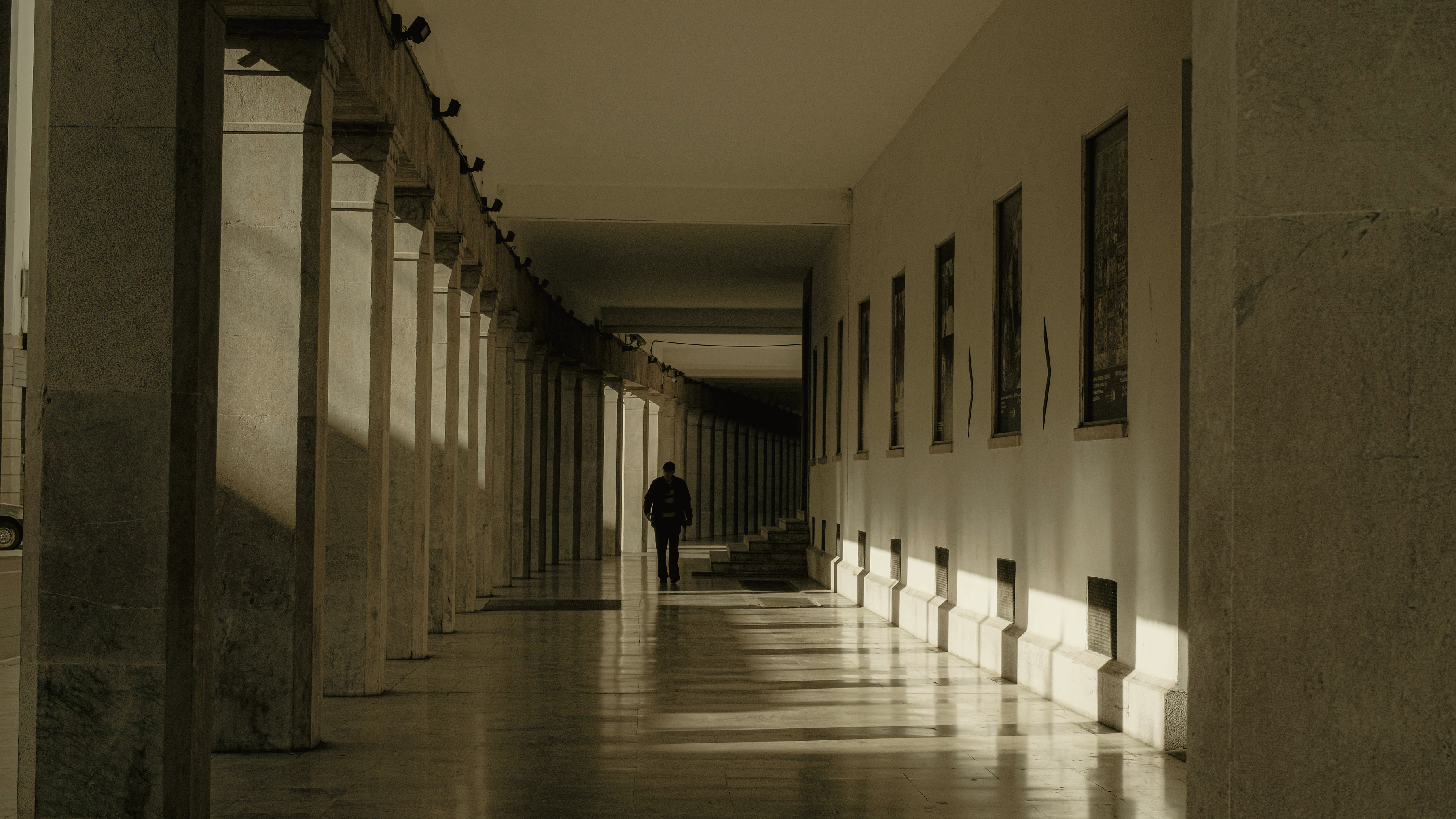 A lit crossing at dusk, one figure walking its length.