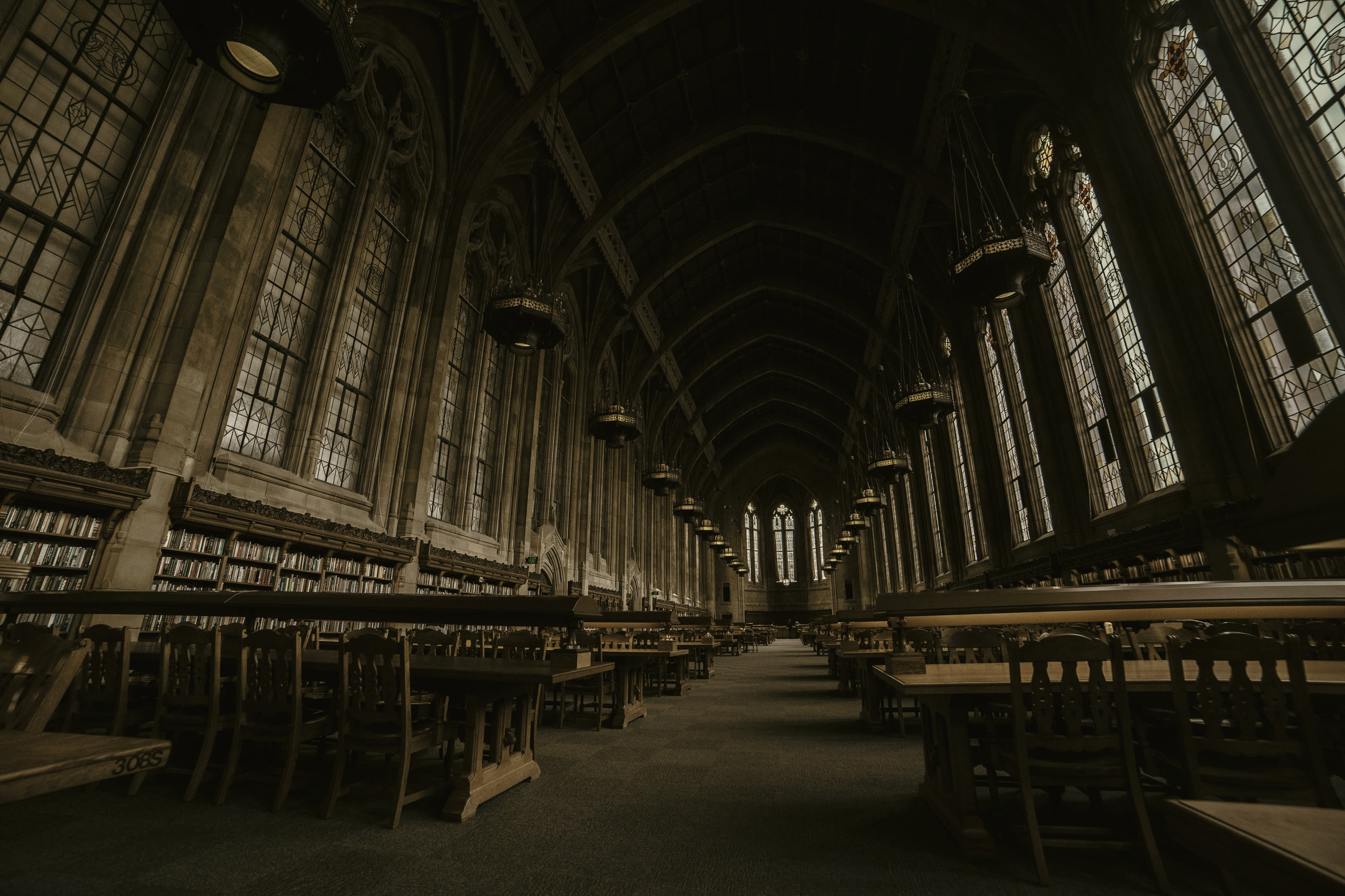 An empty institutional reading hall, desks ranked under a high ceiling.