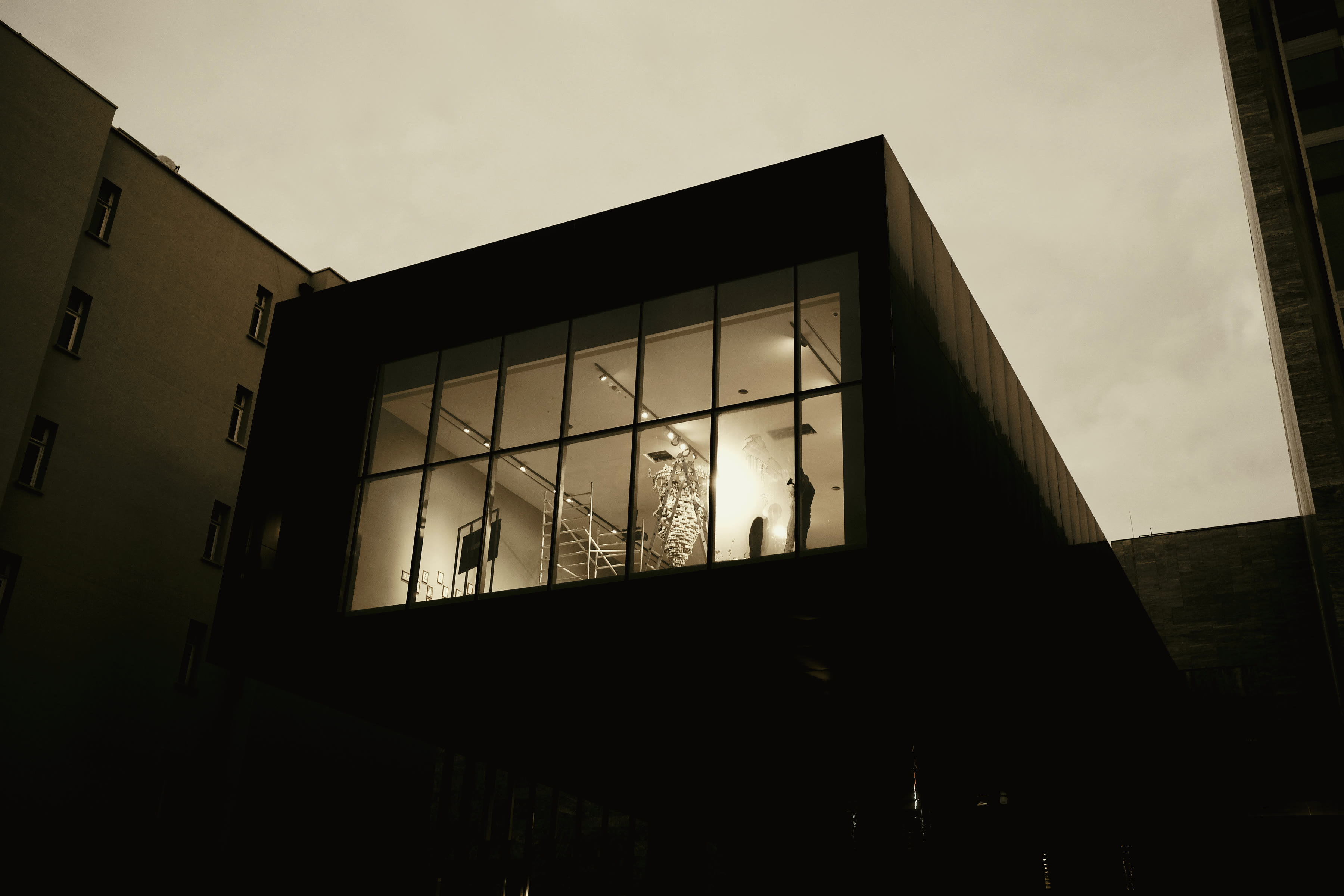 A single building facade at dusk, its lit windows in a repeating grid.