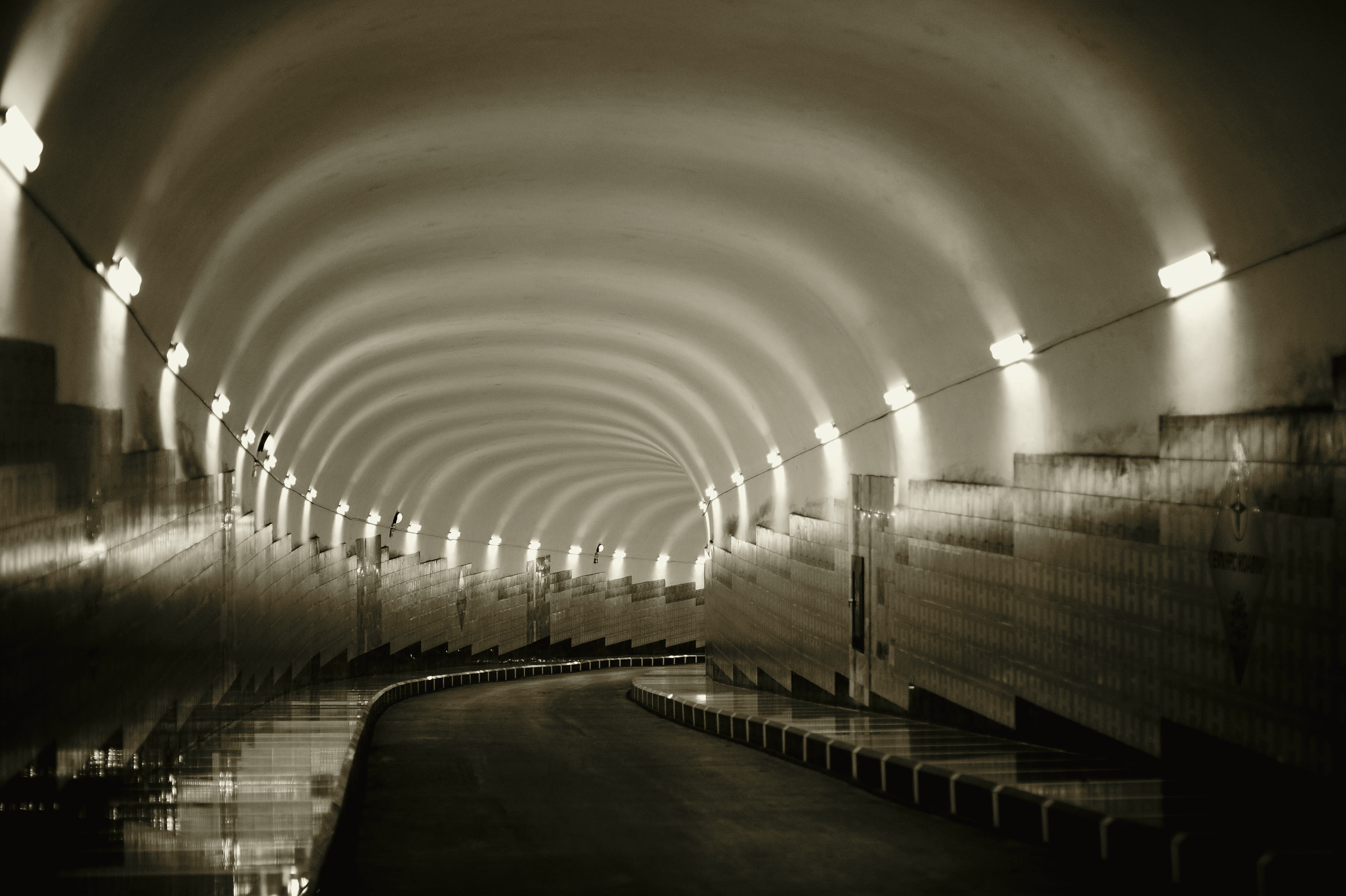 Interior of a large bored tunnel with segmental concrete lining receding into the distance.